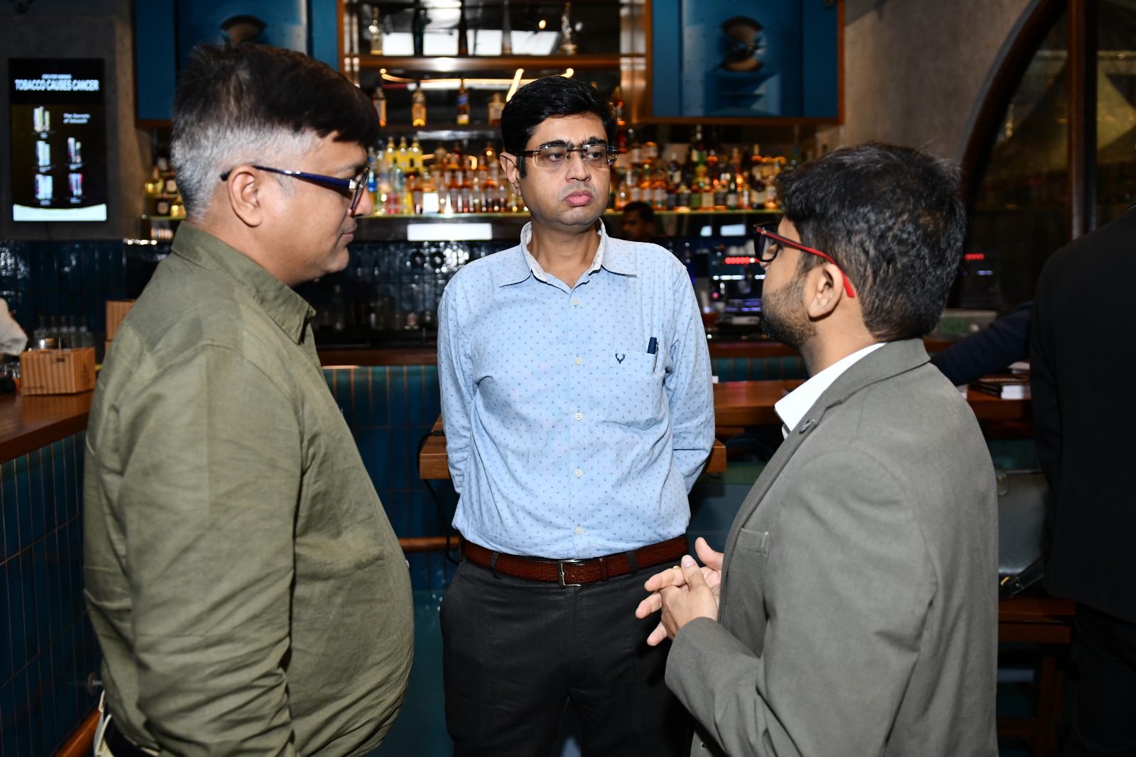 Guests laughing at the bar under the AlphaBlock screen